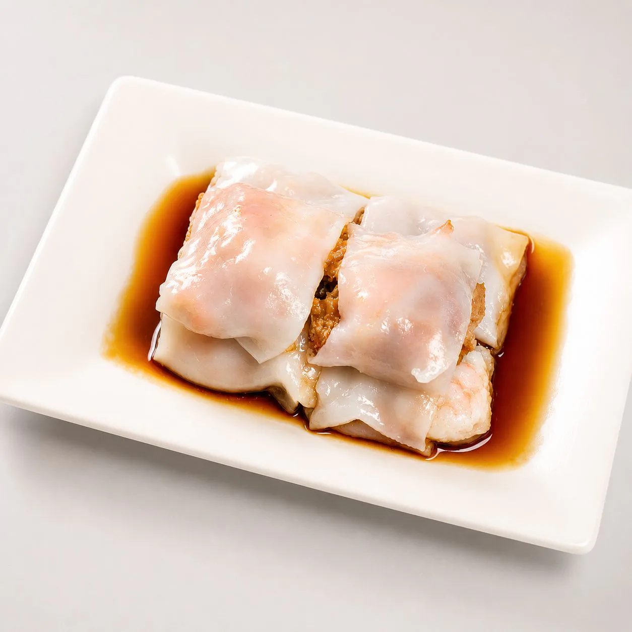 Signature rice noodle roll with soy sauce on white plate