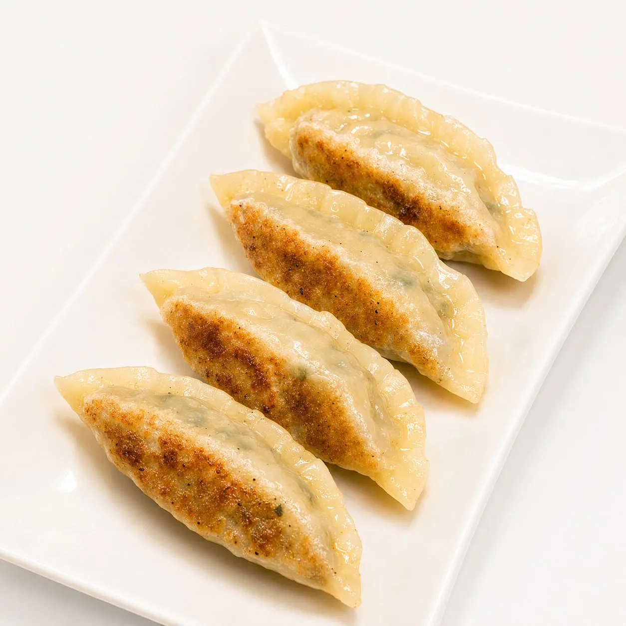 Vegetarian potstickers arranged on white rectangular plate